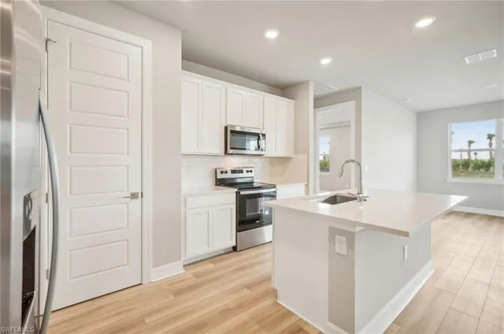 Kitchen featuring white cabinets, sink, a center island with sink, light hardwood / wood-style flooring, and appliances with stainless steel finishes