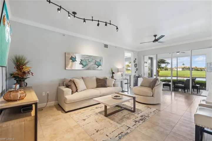 Tiled living room featuring ceiling fan and ornamental molding