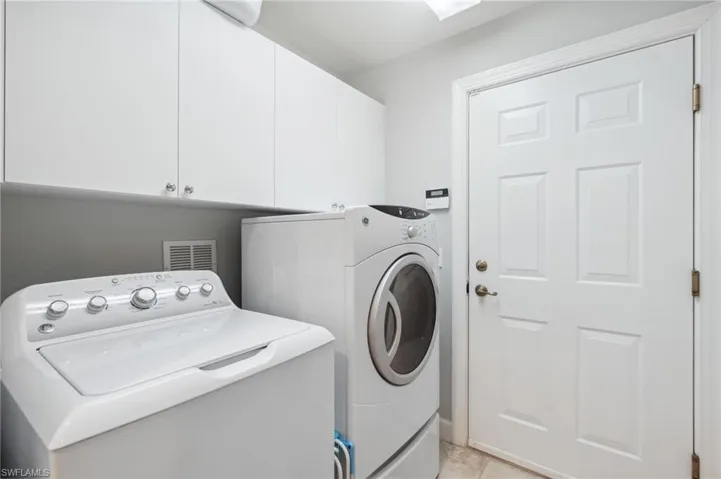 Washroom featuring washing machine and dryer, light tile patterned floors, and cabinets