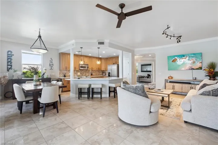 Living room with ceiling fan, crown molding, and light tile patterned flooring