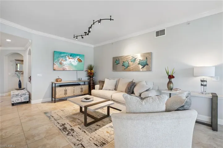 Living room with light tile patterned floors and crown molding