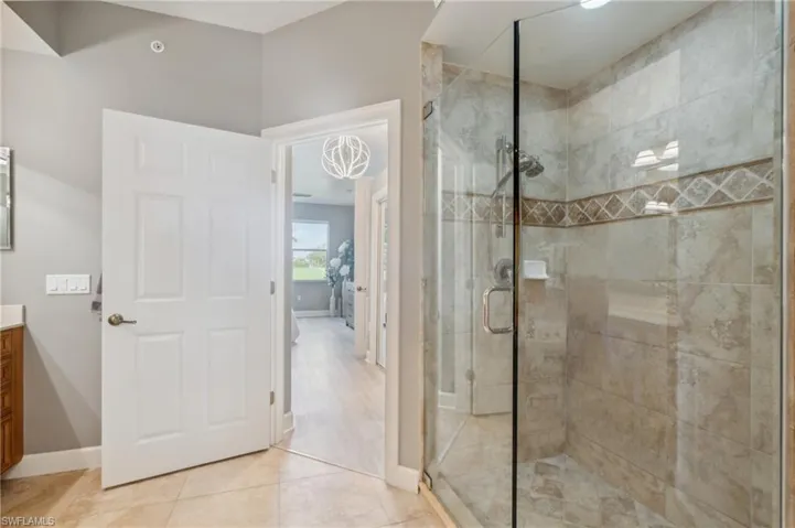 Bathroom featuring tile patterned floors, vanity, and a shower with door