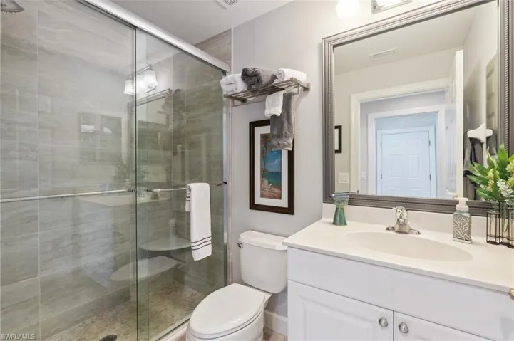 Bathroom featuring an enclosed shower, vanity, and toilet