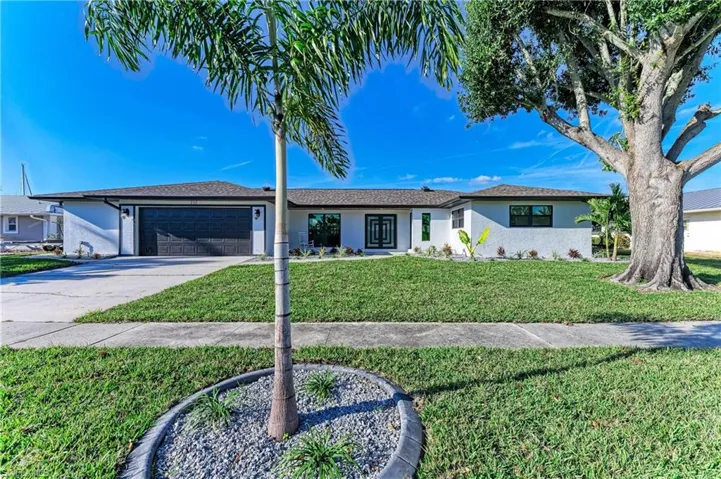 Ranch-style house with a front lawn, stucco siding, driveway, and an attached garage