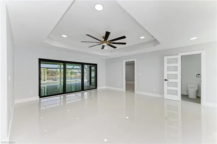 Empty room featuring a raised ceiling, a ceiling fan, recessed lighting, and light tile patterned flooring