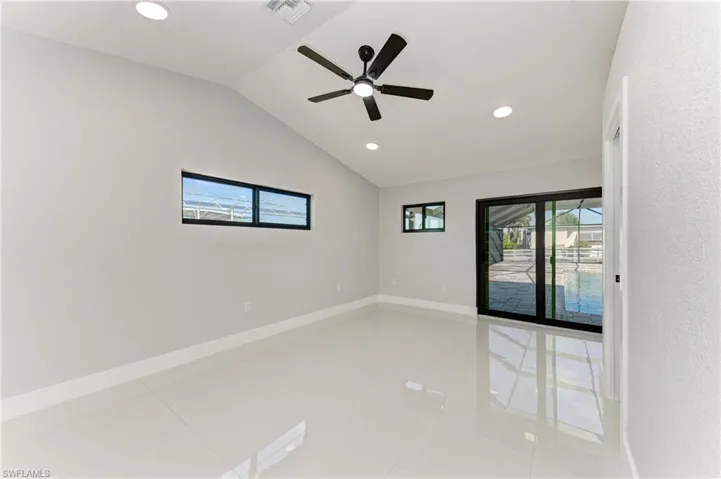 Spare room with lofted ceiling, healthy amount of natural light, recessed lighting, light tile patterned floors, and ceiling fan