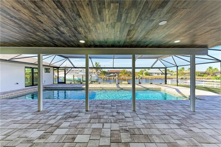 Outdoor pool with a patio area, glass enclosure, and a sunroom