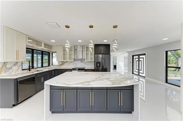 Kitchen featuring glass insert cabinets, plenty of natural light, light stone counters, and recessed lighting