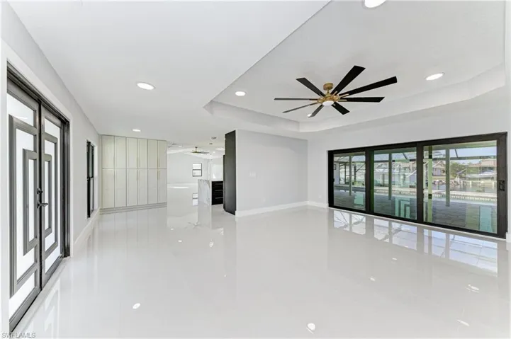 Unfurnished living room featuring a tray ceiling, recessed lighting, ceiling fan, and light tile patterned flooring