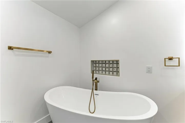 Full bath with a soaking tub and lofted ceiling