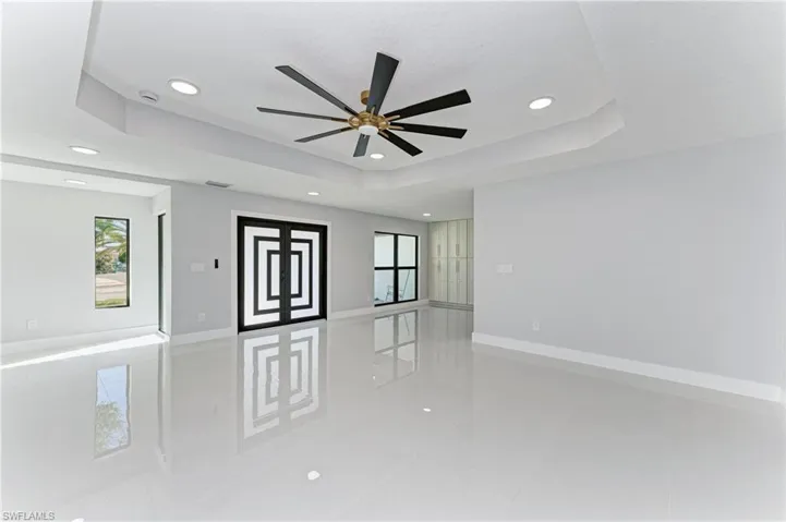 Spare room featuring a tray ceiling, light tile patterned floors, a ceiling fan, and recessed lighting