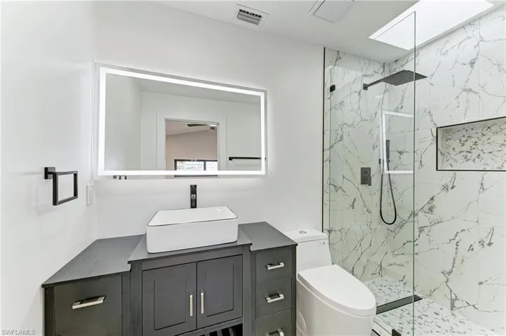 Bathroom with vanity and a marble finish shower