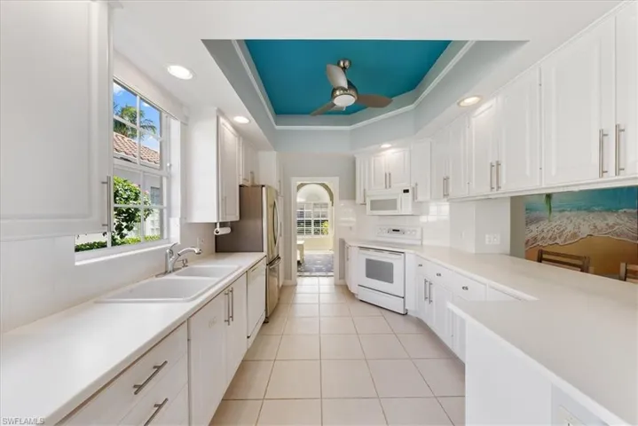Kitchen featuring white cabinets, a ceiling fan, and white appliances
