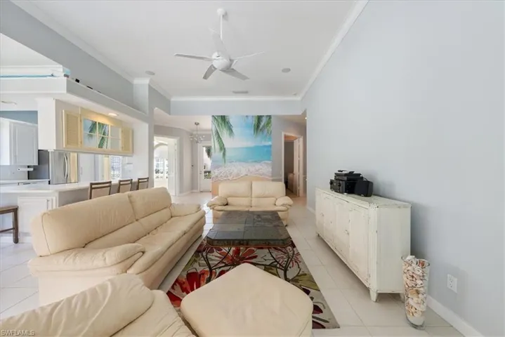 Living area featuring baseboards, ceiling fan, ornamental molding, and light tile patterned floors