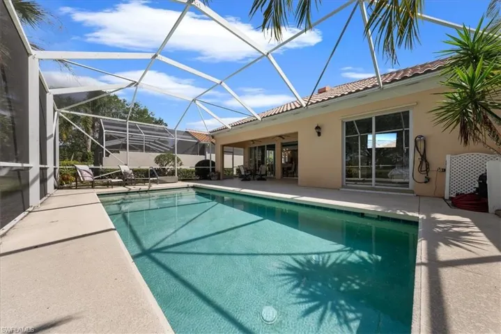 Outdoor pool with glass enclosure, a ceiling fan, and a patio area