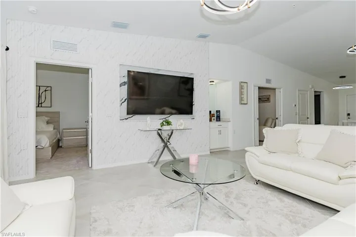 Living room with lofted ceiling, baseboards, and light tile patterned flooring