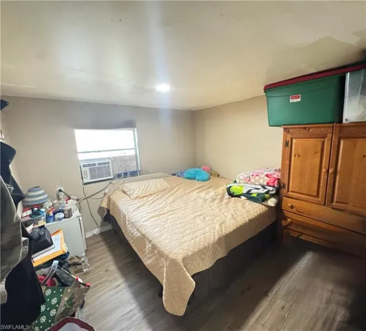Bedroom with wood finished floors and cooling unit