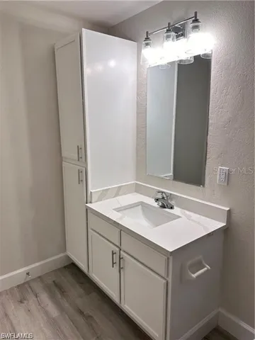 Bathroom featuring vanity, light wood-style floors, and a textured wall