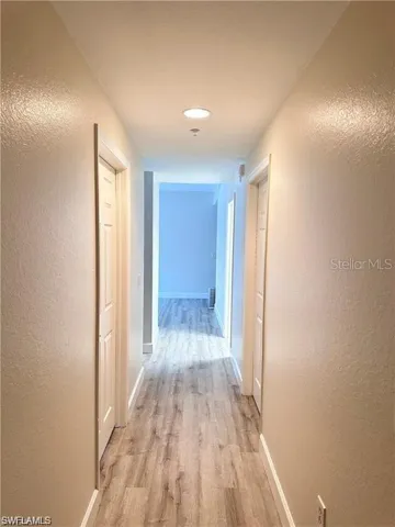 Hall featuring a textured wall and light wood finished floors