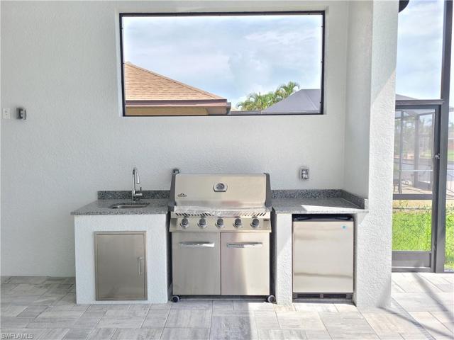 Outdoor kitchen with a 5-burner stainless grill from Napoleon and a stainless steel refrigerator