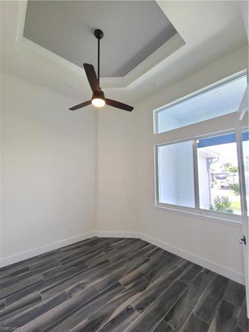 Study with large window, high tray ceiling and dark grey plank tile