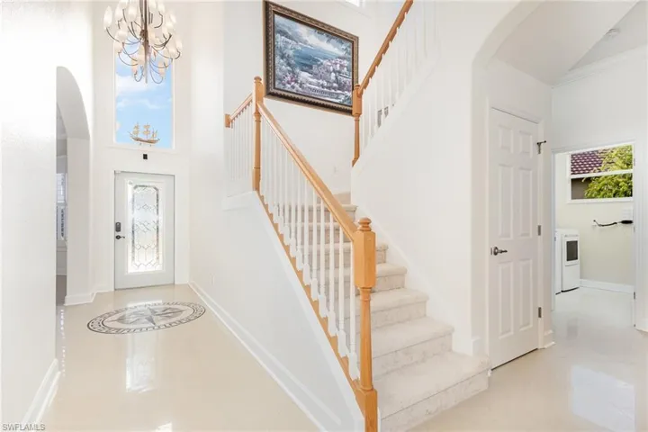 Entrance foyer with arched walkways, plenty of natural light, light tile patterned floors, and a high ceiling