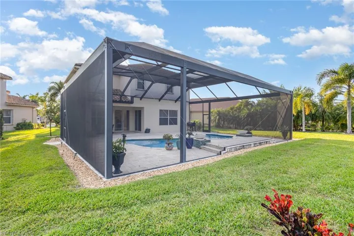 Rear view of house featuring an outdoor pool, a sunroom, a lanai, a patio, and a lawn