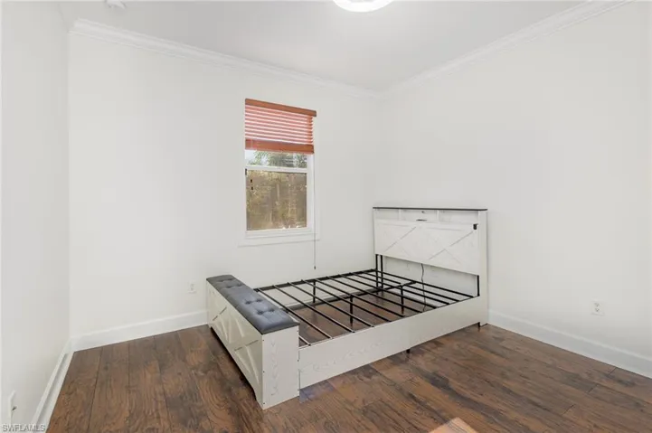 Unfurnished bedroom with crown molding and dark wood-type flooring