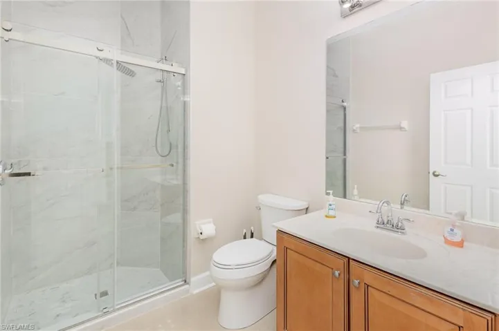 Full bathroom with vanity, a marble finish shower, and light tile patterned floors