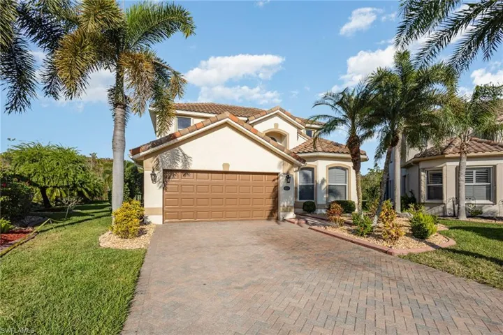 Mediterranean / spanish-style house featuring stucco siding, decorative driveway, a front lawn, and a garage