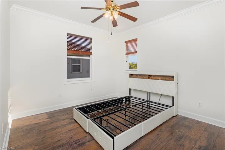 Unfurnished bedroom with crown molding, dark wood-style flooring, and a ceiling fan