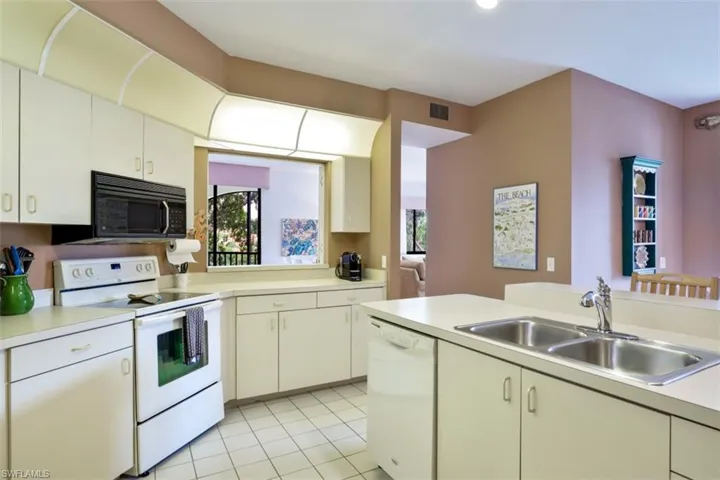Kitchen featuring white appliances, light countertops, healthy amount of natural light, and light tile patterned flooring