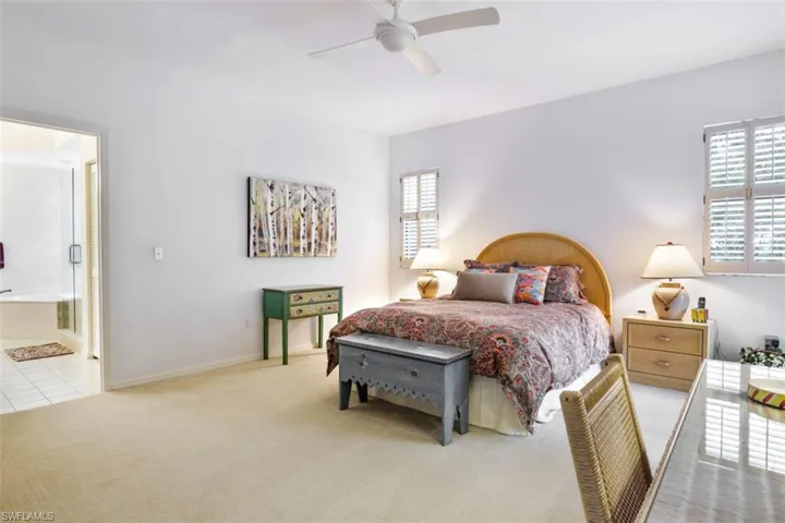 Carpeted bedroom with ensuite bath, a ceiling fan, and tile patterned floors