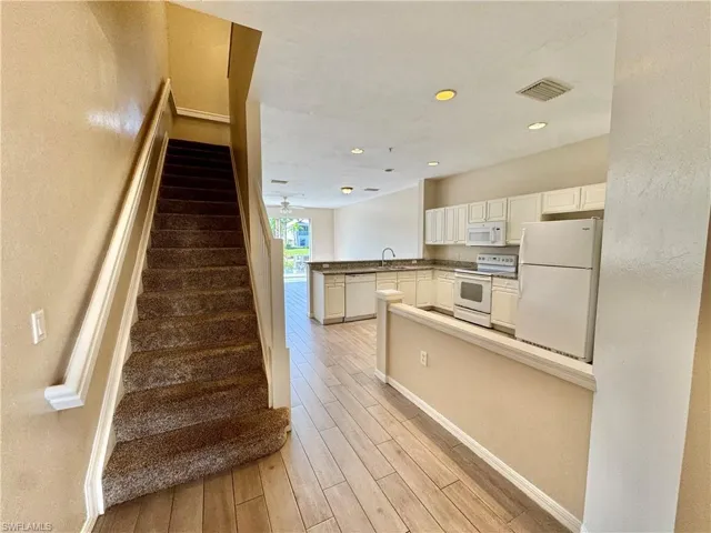 Stairway featuring wood finished floors, recessed lighting, and a textured wall