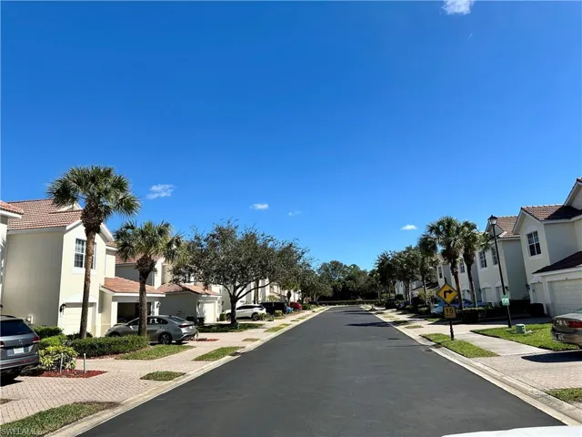 View of asphalt street featuring a residential view, sidewalks, traffic signs, and curbs