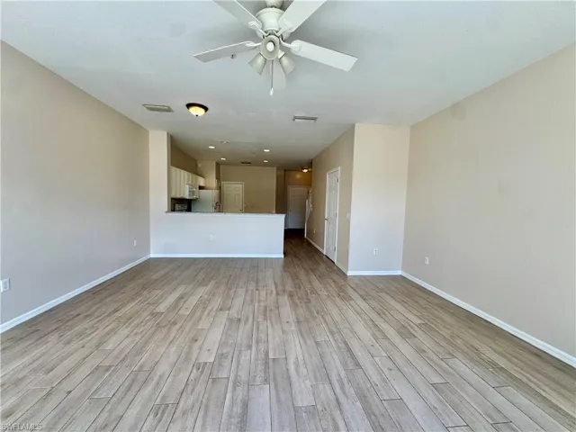 Unfurnished living room with light wood-type flooring and ceiling fan