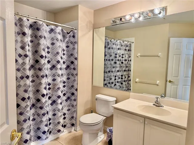 Full bathroom featuring light tile patterned flooring, vanity, and a shower stall