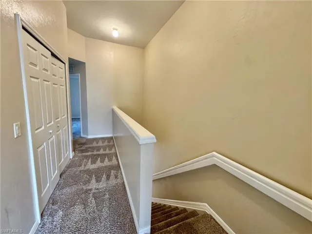 Hall with carpet floors and an upstairs landing
