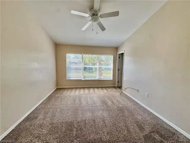 Carpeted empty room with baseboards and a ceiling fan
