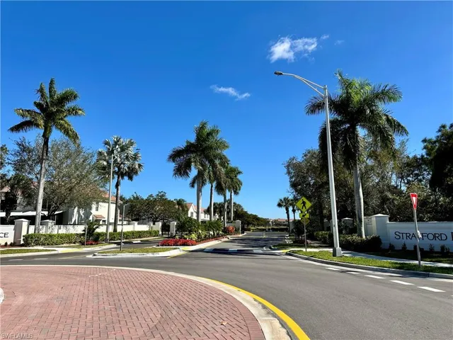 View of asphalt road with sidewalks, street lighting, curbs, and traffic signs
