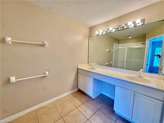 Full bathroom with double vanity, a stall shower, and light tile patterned flooring