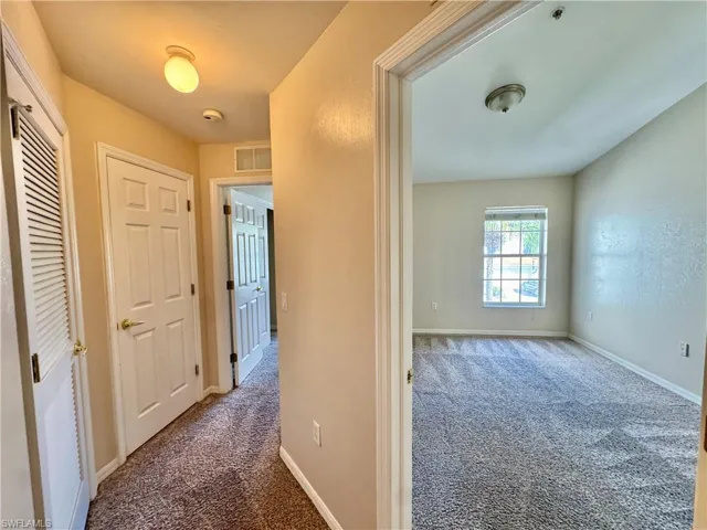 Hall with dark carpet and baseboards