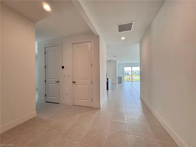 Corridor with baseboards, visible vents, recessed lighting, and light tile patterned floors