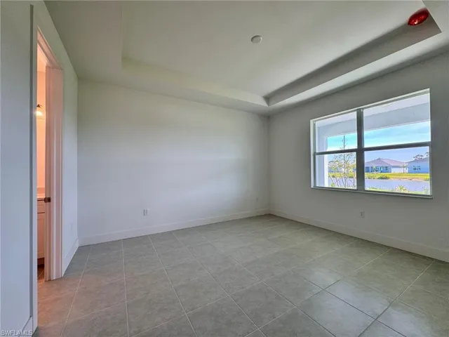 Large primary bedroom with tray ceiling and lake view.