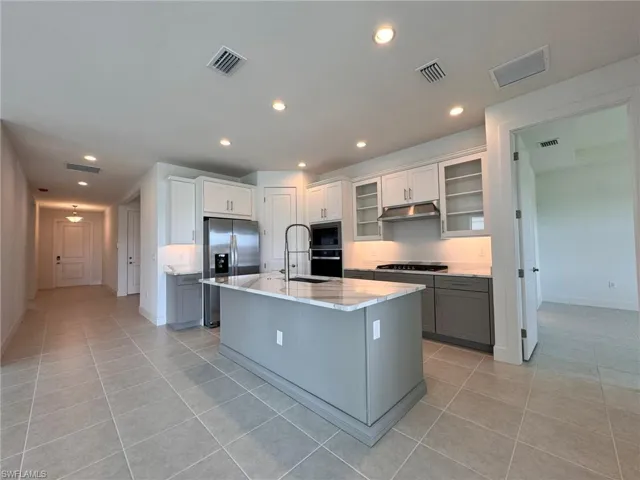 Kitchen featuring visible vents, stainless steel refrigerator with ice dispenser, under cabinet range hood, and built in microwave