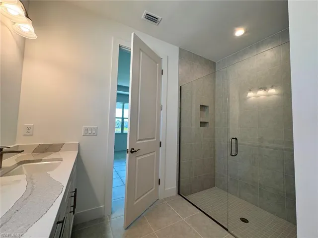 Full bathroom with vanity, baseboards, tile patterned floors, a stall shower, and visible vents