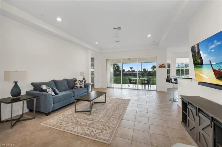 Living room with a raised ceiling, ceiling fan, plenty of natural light, and light tile patterned floors