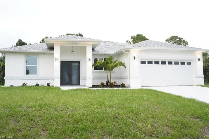 View of front facade featuring stucco siding, an attached garage, driveway, a front lawn, and roof with shingles