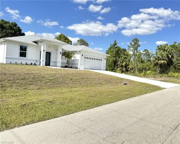 View of front facade with a garage, stucco siding, concrete driveway, and a front yard
