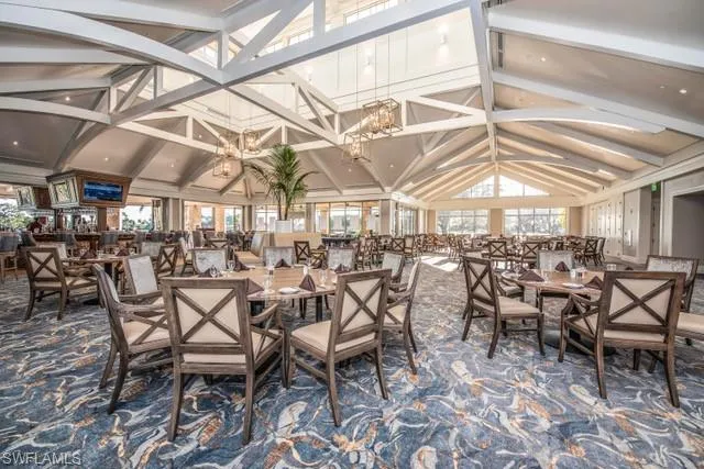 Carpeted dining room featuring vaulted ceiling with beams, a chandelier, and a wealth of natural light